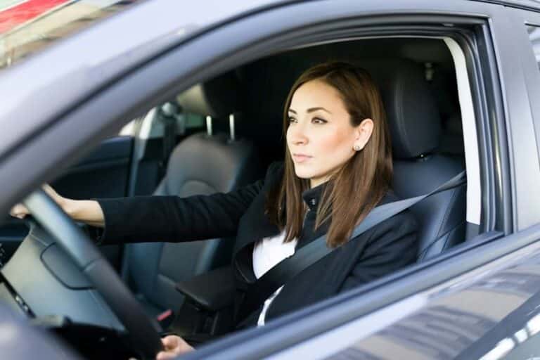 A young woman in corporate wear, driving a black car