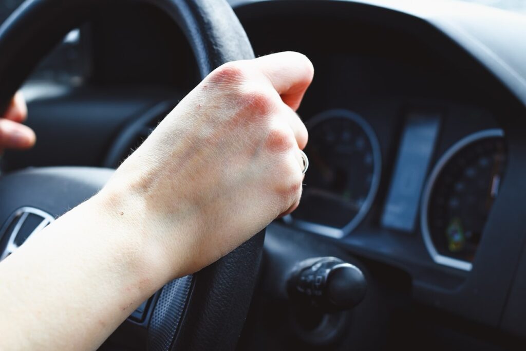 A hand on a black steering wheel
