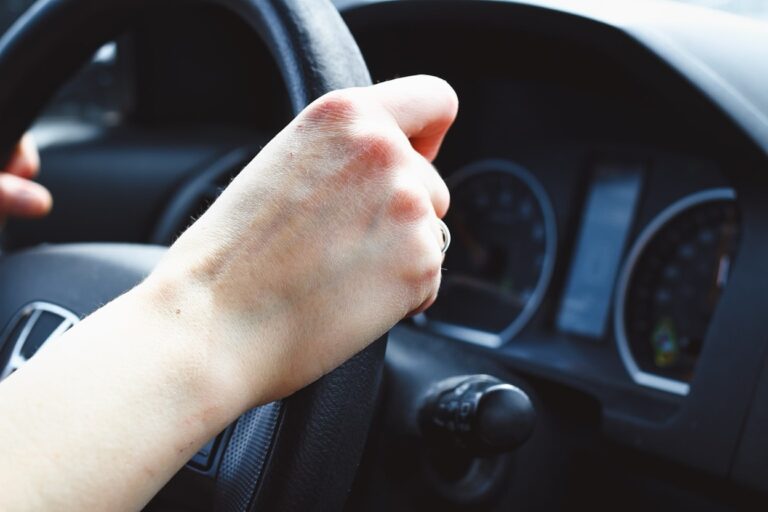 A hand on a black steering wheel