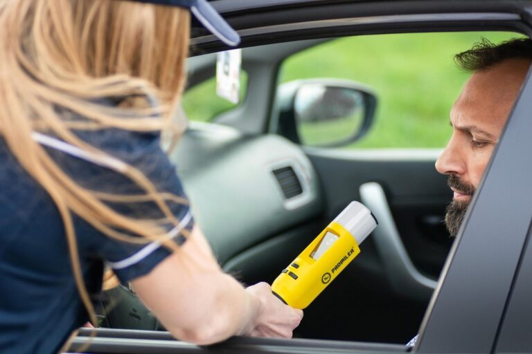 Officer administering a roadside breathalyzer test to a driver during a traffic stop in Texas.