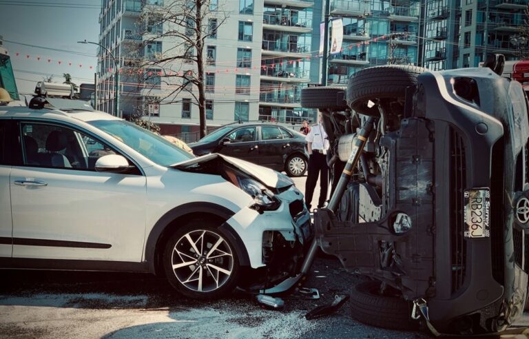 Two vehicles are involved in a serious collision, with one car flipped on its side in an urban area