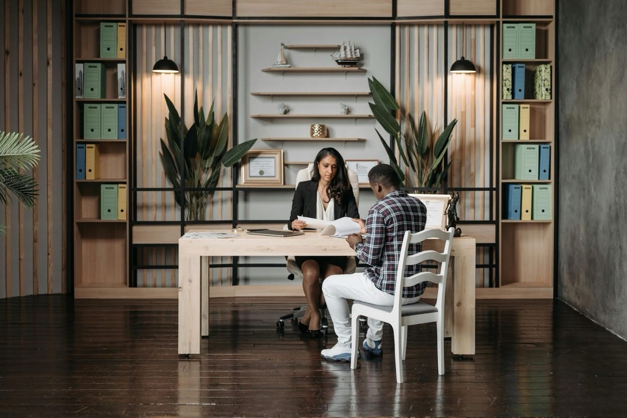 A female attorney reviews documents with a male client at a desk