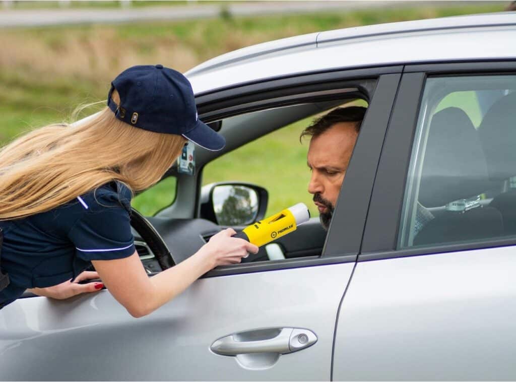 A female police officer administering a breathalyzer test to a male driver