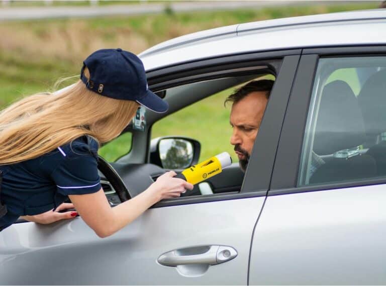 A female police officer administering a breathalyzer test to a male driver