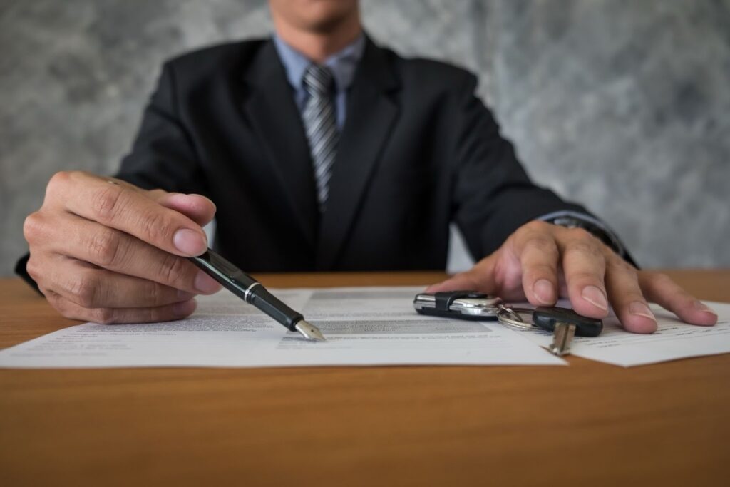 A lawyer in a suit pointing a pen at documents on a desk