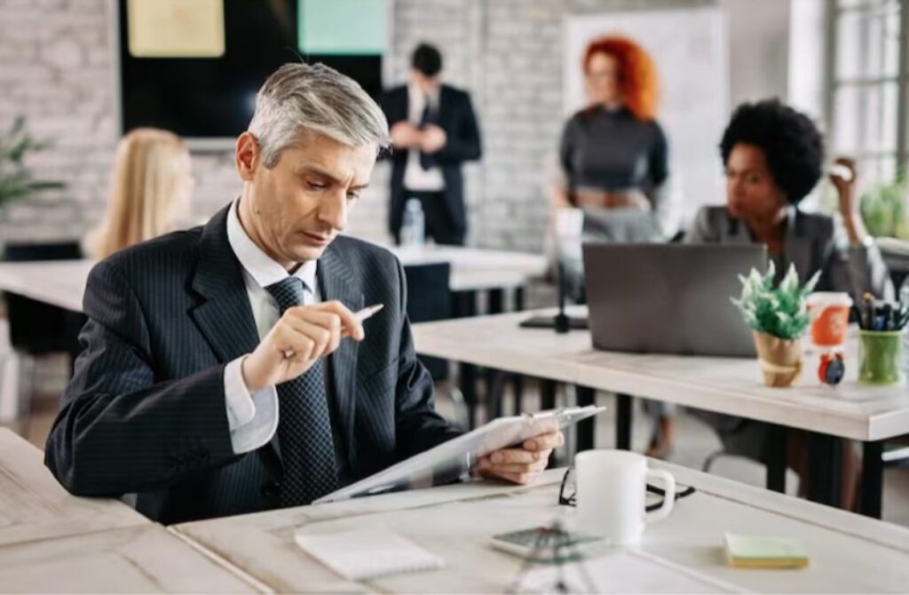 An attorney in a suit reviews documents on a tablet in a busy office environment